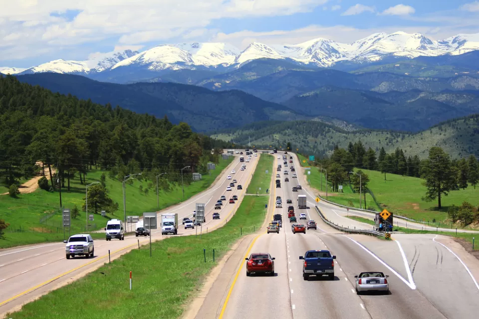 Cars on highway in Colorado with snow-capped mountains in background